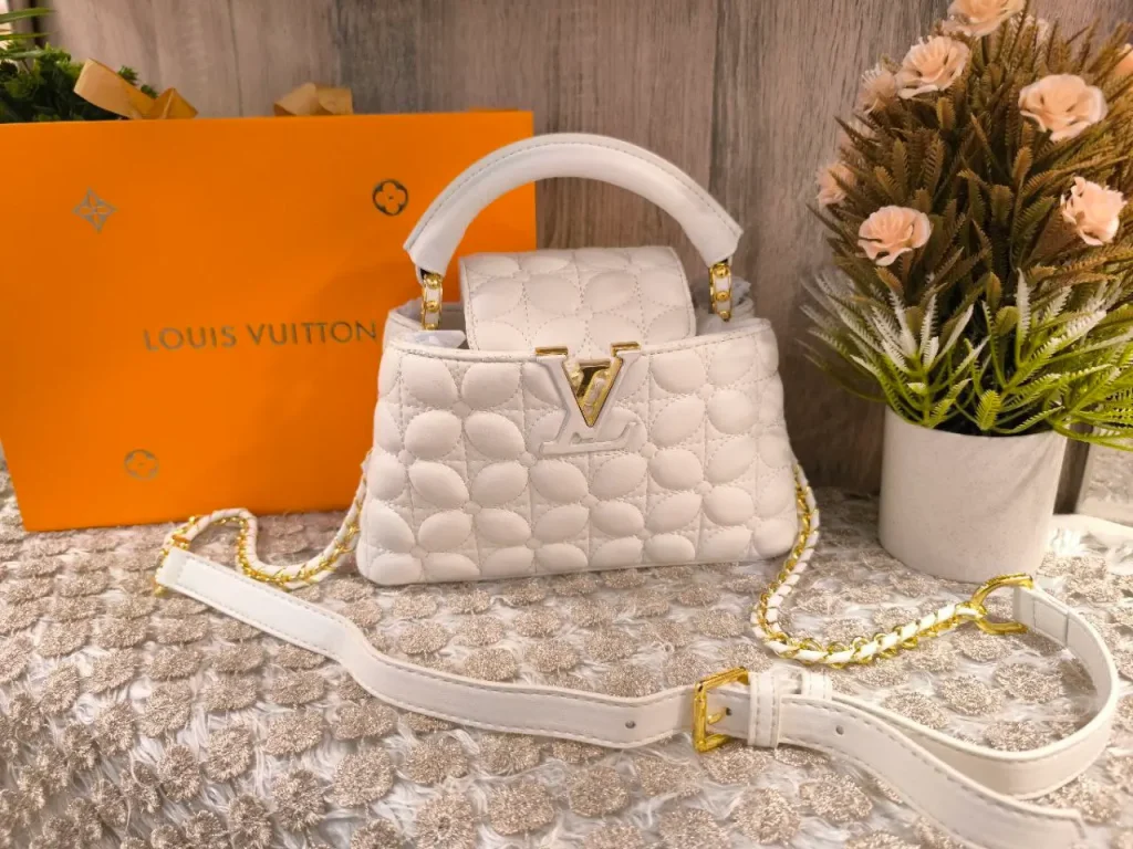 Louis Vuitton Quilted Vanity Bag (Cannes style), White soft leather with circular quilting, rigid top handle, bold gold-tone V logo, and gold chain crossbody strap.